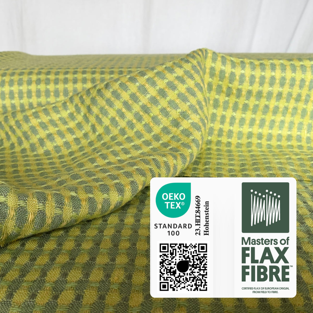 Draped yellow and green linen fabric with a textured pattern and OEKO-TEX® Standard 100 and Masters of FLAX FIBRE™ labels