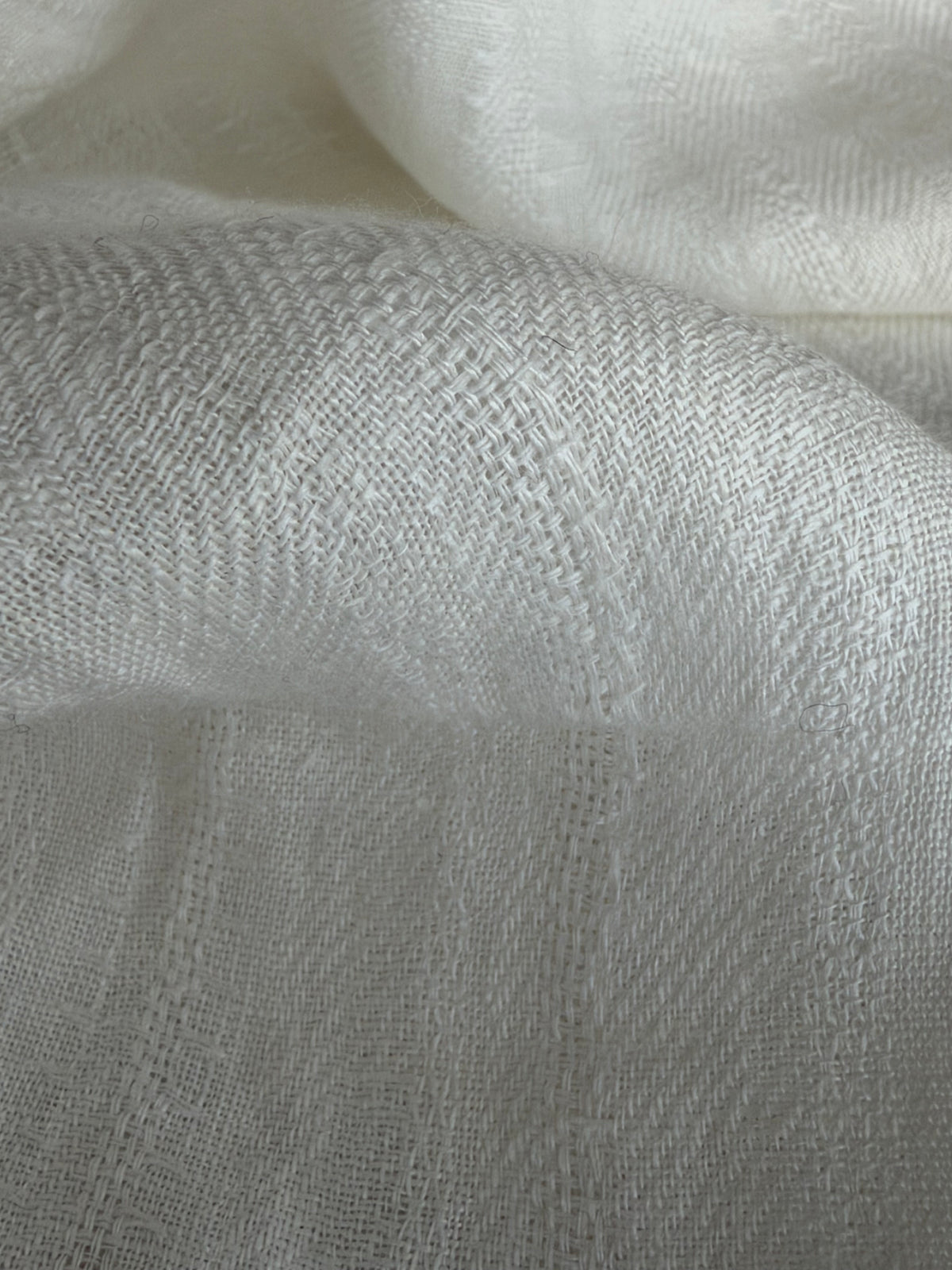 A close-up of draped white woven fabric with a soft, textured surface.