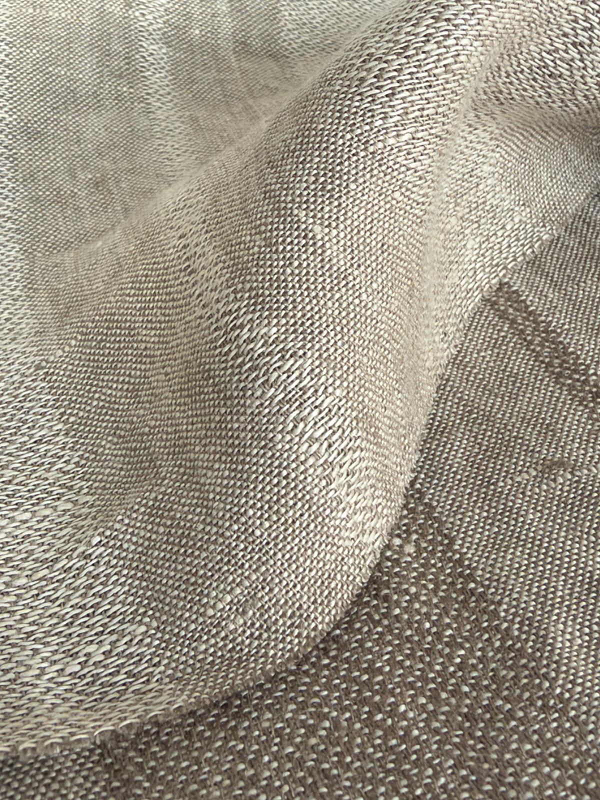 A close-up of draped woven fabric with a textured, ribbed pattern in light taupe and gray-beige tones.