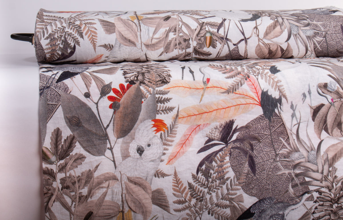 A close-up of a rolled and draped fabric featuring a detailed botanical and bird pattern in muted earth tones with small bright red-orange accents.