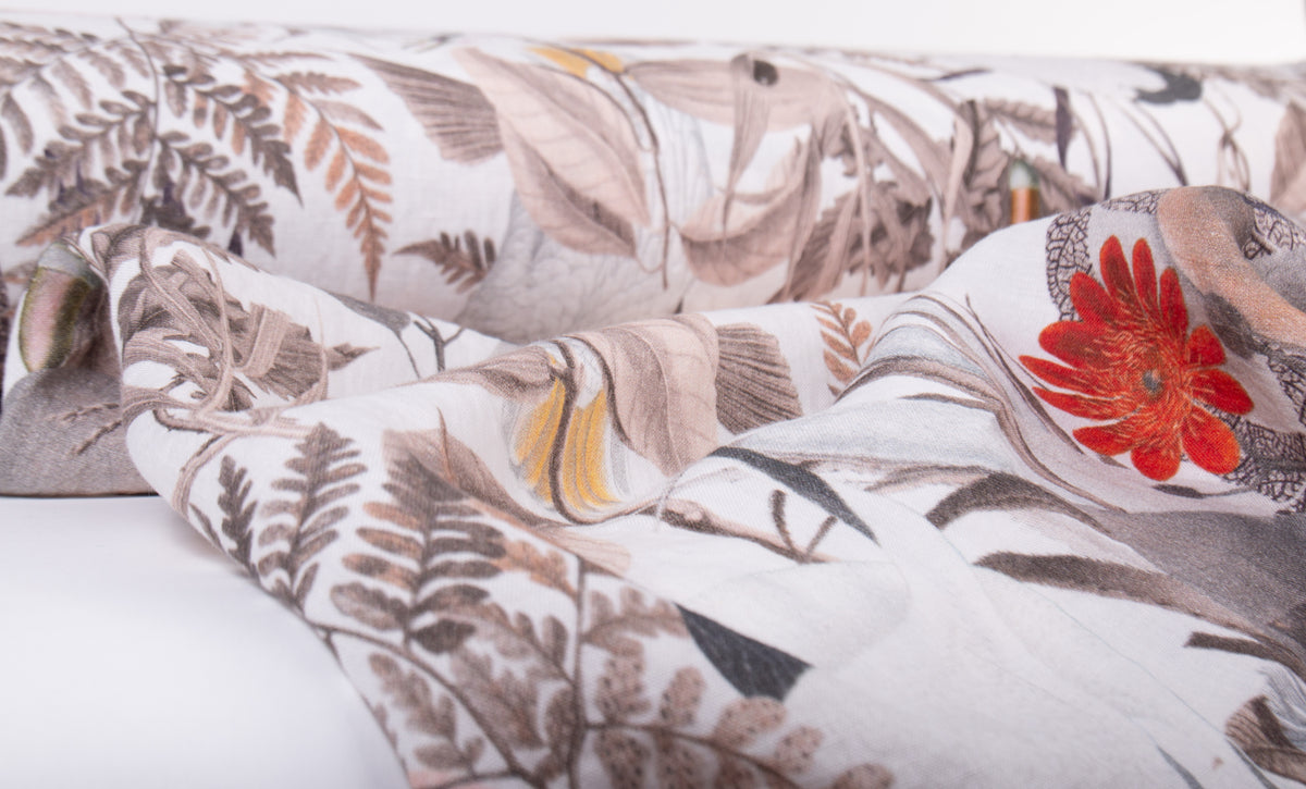 A close-up of a patterned duvet cover or comforter with a botanical design featuring ferns, leaves, and a prominent red flower on a white background.
