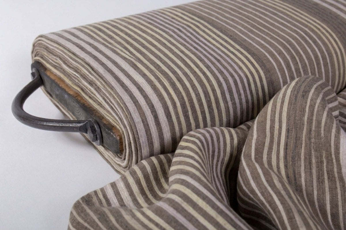 Roll of brown and beige striped fabric with a metal handle on a white background