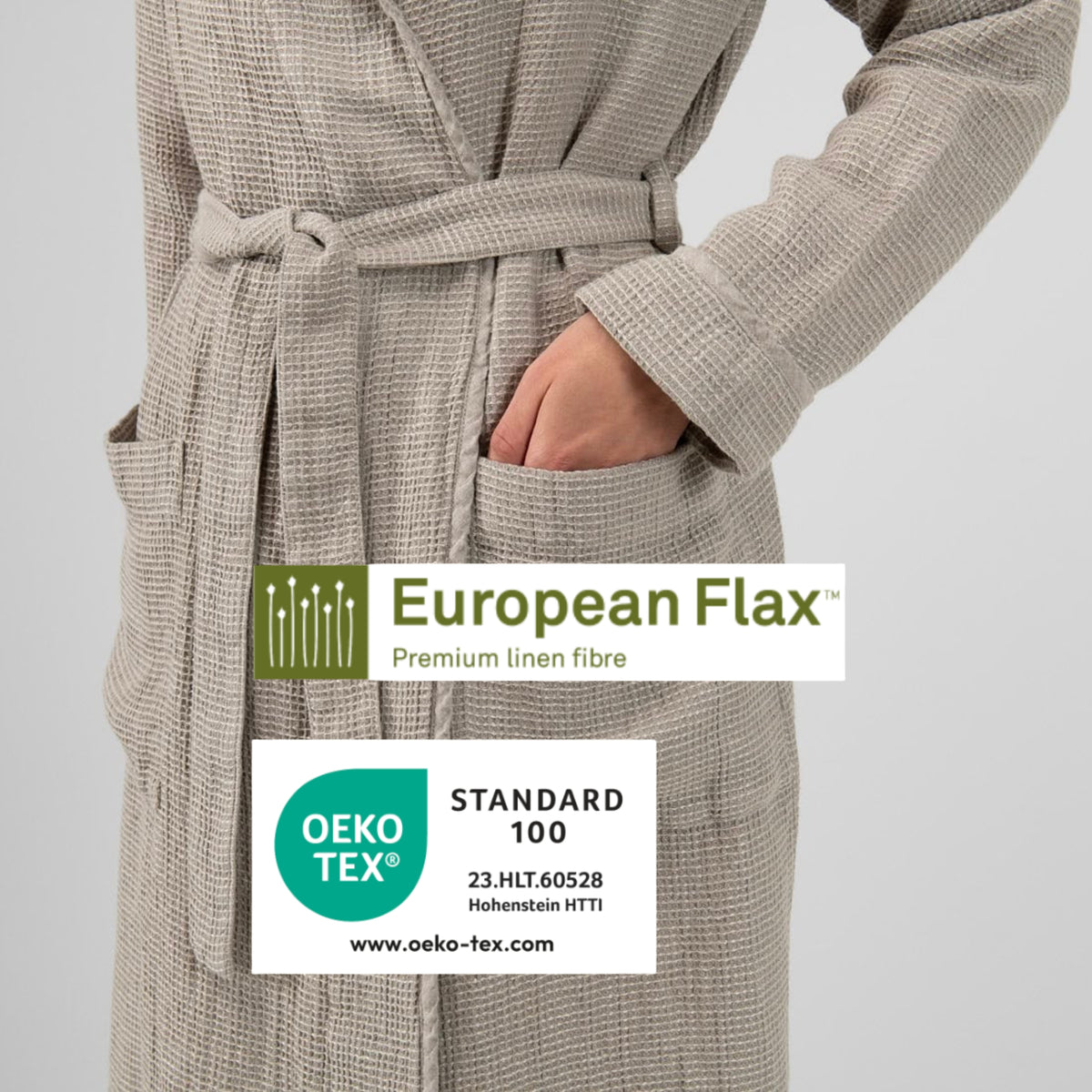 A close-up of a person wearing a beige textured waffle-weave robe with a matching belt and front pockets, with a hand in the pocket. Two certification badges are overlaid on the lower center: a European Flax badge and an OEKO-TEX Standard 100 badge.