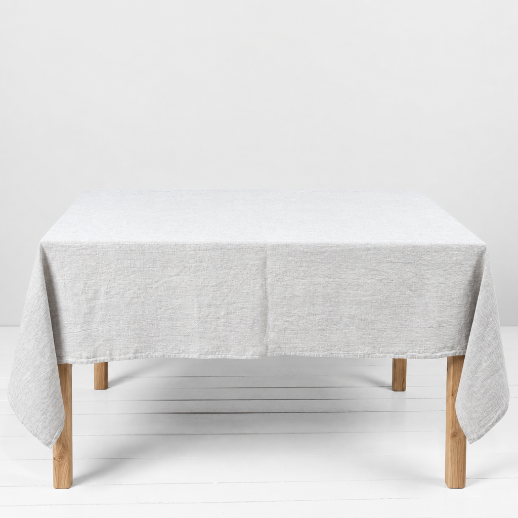 Washed linen tablecloth on a table with natural wood legs, with no objects on the table