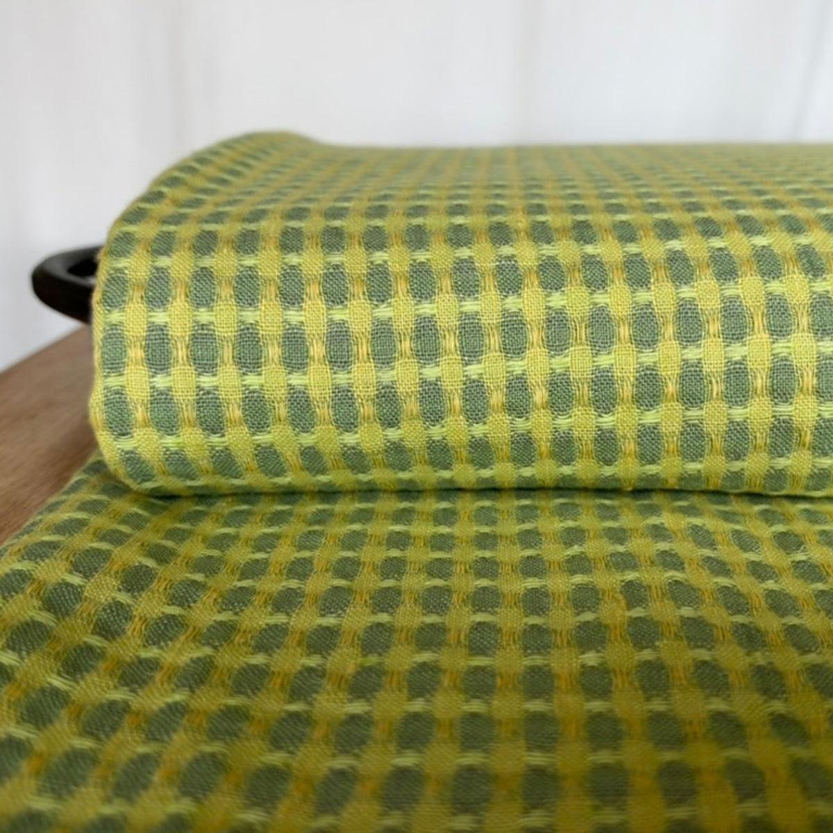 Close-up of yellow and green washed linen fabric with a textured woven pattern