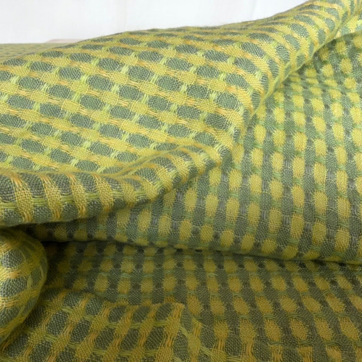 Folded yellow and green linen fabric showing its textured pattern