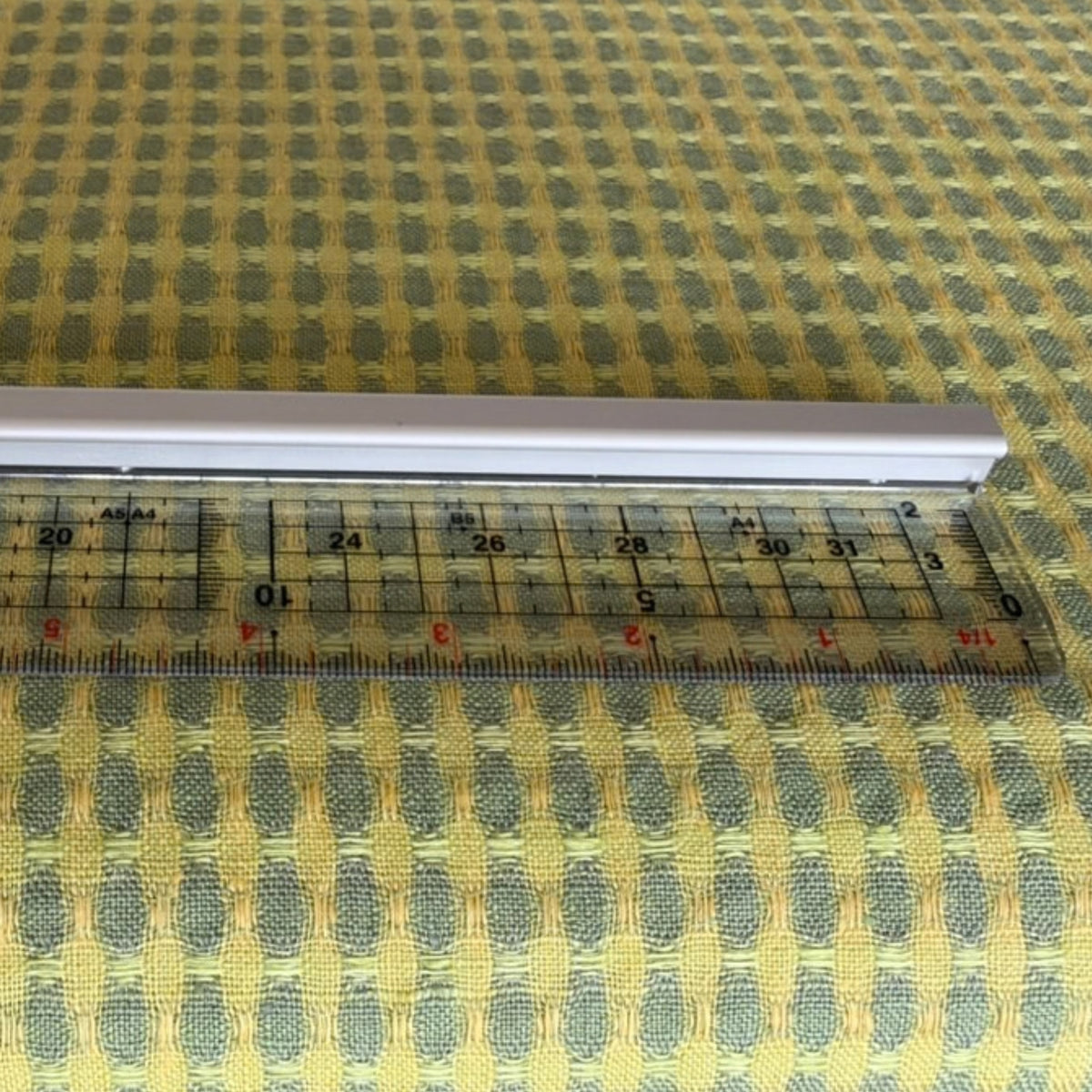 Yellow and green patterned linen fabric shown beside a ruler